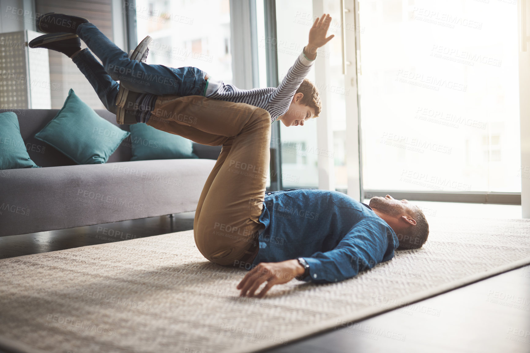 Buy stock photo Airplane, happy and dad playing with kid for bonding, healthy relationship and relax in living room. Family, home and father and young boy have fun for flying, balance and playful games on floor