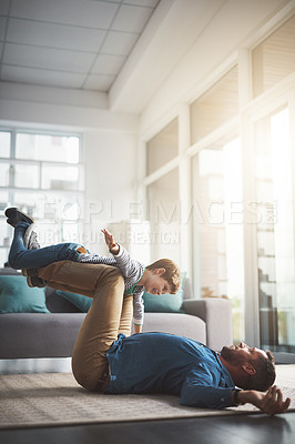 Buy stock photo Shot of a cheerful little boy playing around and being lifted by his dad with his legs in the living room at home during the day