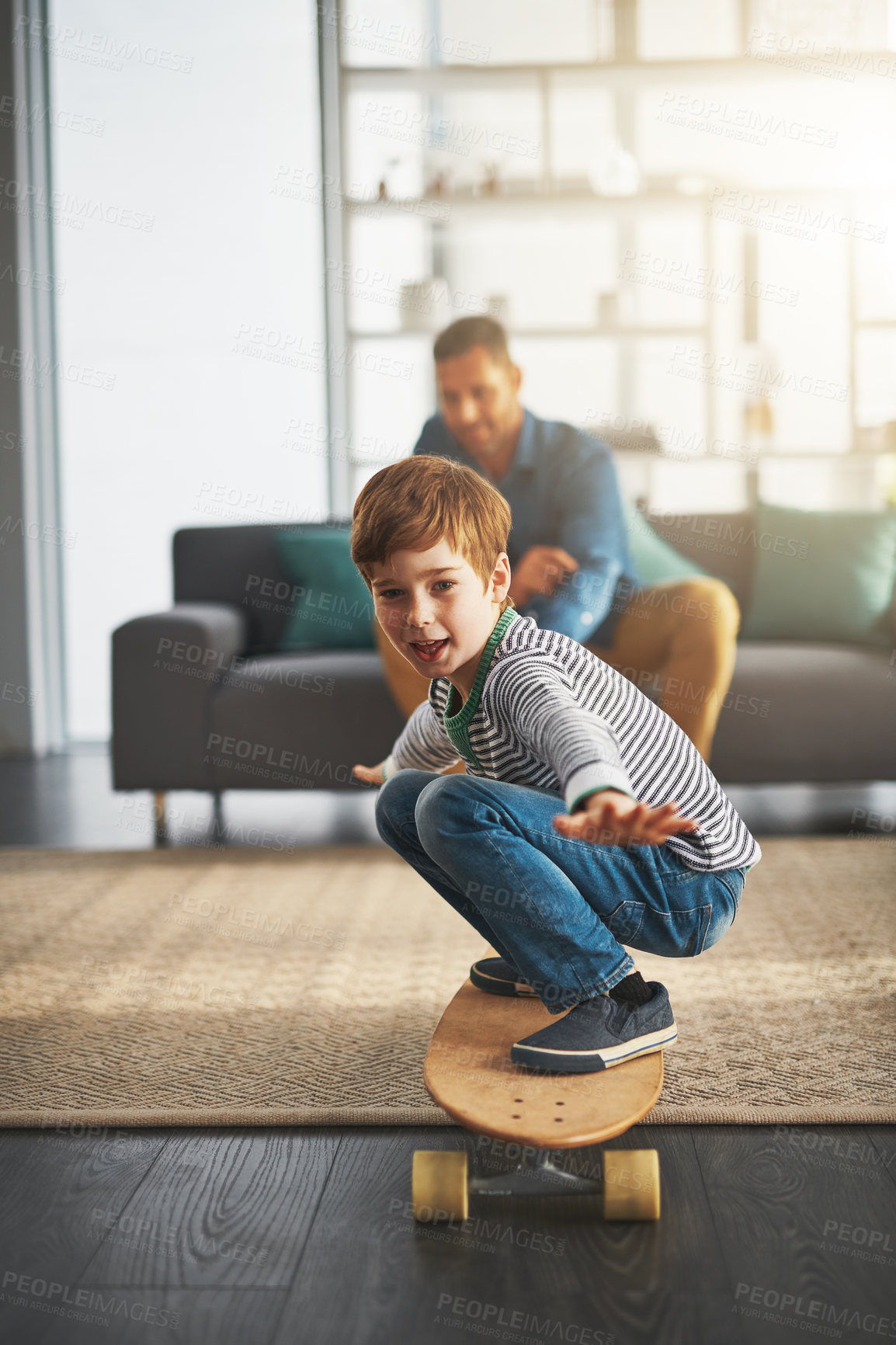 Buy stock photo Shot of a cheerful little boy riding on a surfboard in the middle of the living room at home
