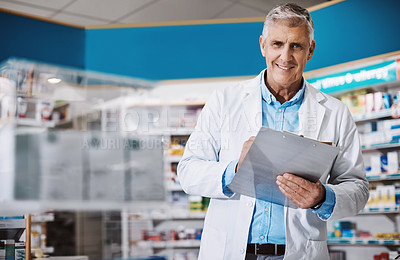 Buy stock photo Shot of a male pharmacist writing on a clipboard in a drugstore