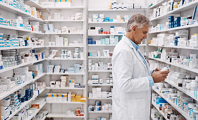 Buy stock photo Shot of a pharmacist reading the label on a product in a drugstore