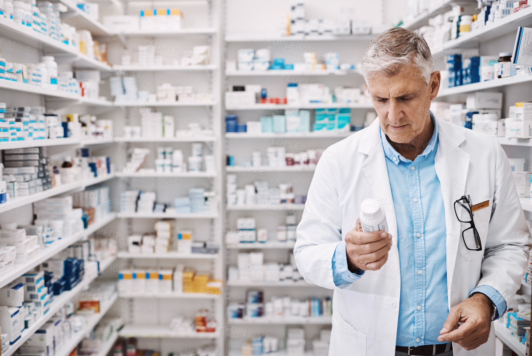 Buy stock photo Shot of a pharmacist reading the label on a product in a drugstore