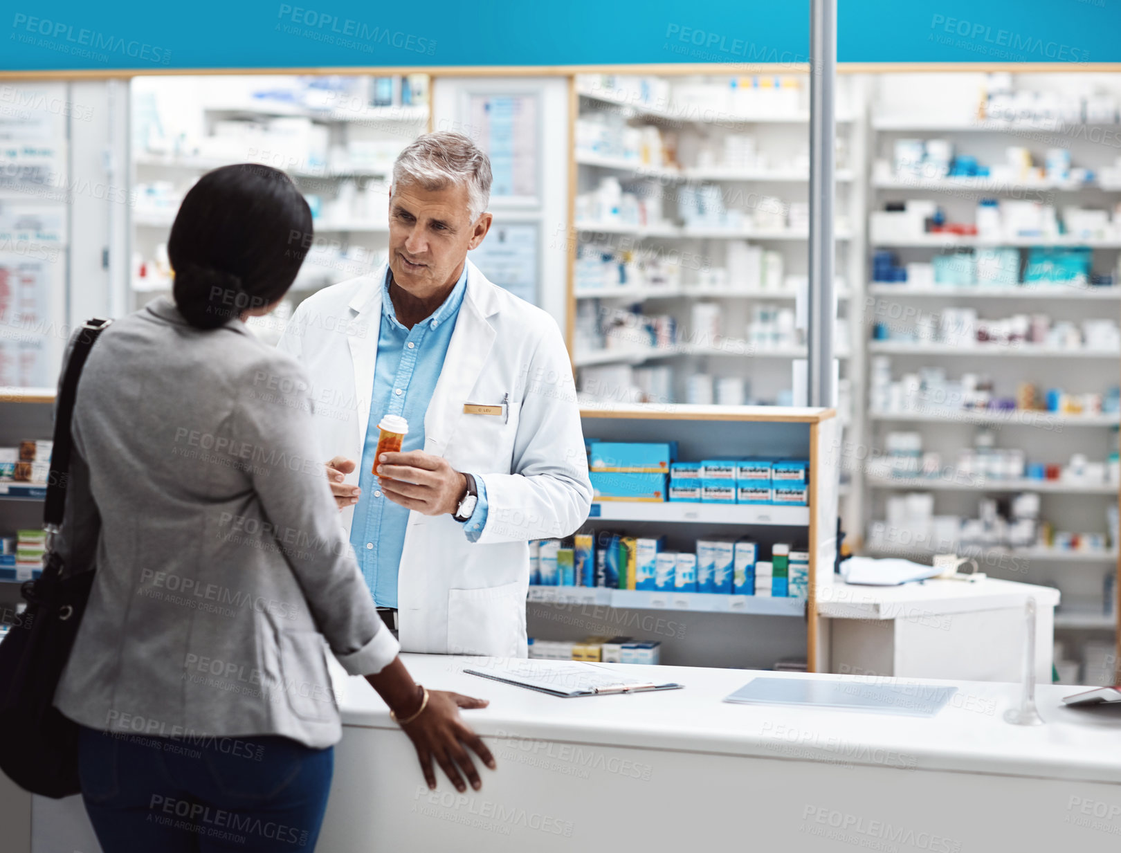 Buy stock photo Shot of a male pharmacist assisting a customer in a chemist