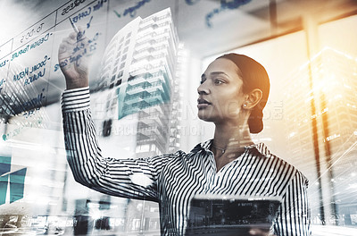 Buy stock photo Shot of a young businesswoman using a digital tablet while writing notes on a glass wall in an office