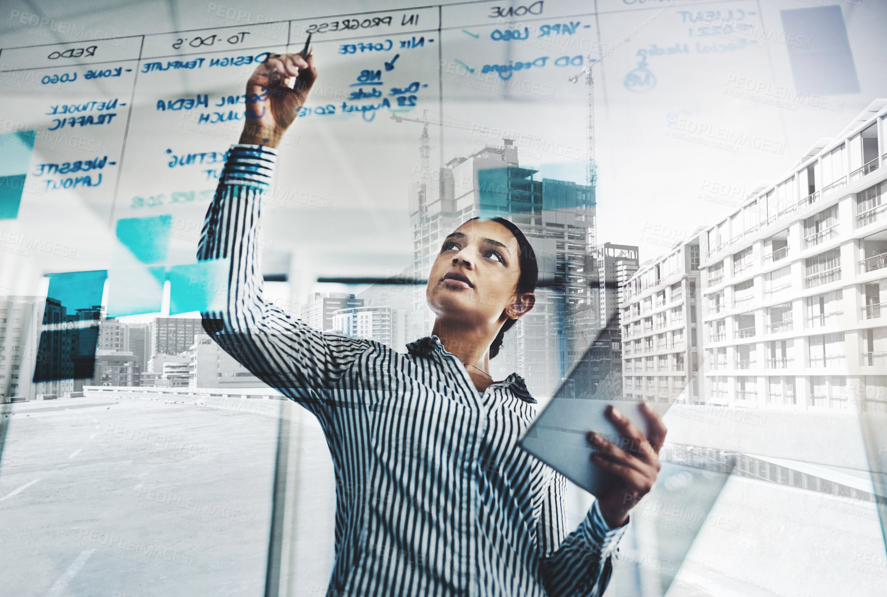 Buy stock photo Shot of a young businesswoman using a digital tablet while writing notes on a glass wall in an office