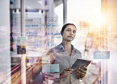 Buy stock photo Shot of a young businesswoman using a digital tablet while brainstorming on a glass wall in an office