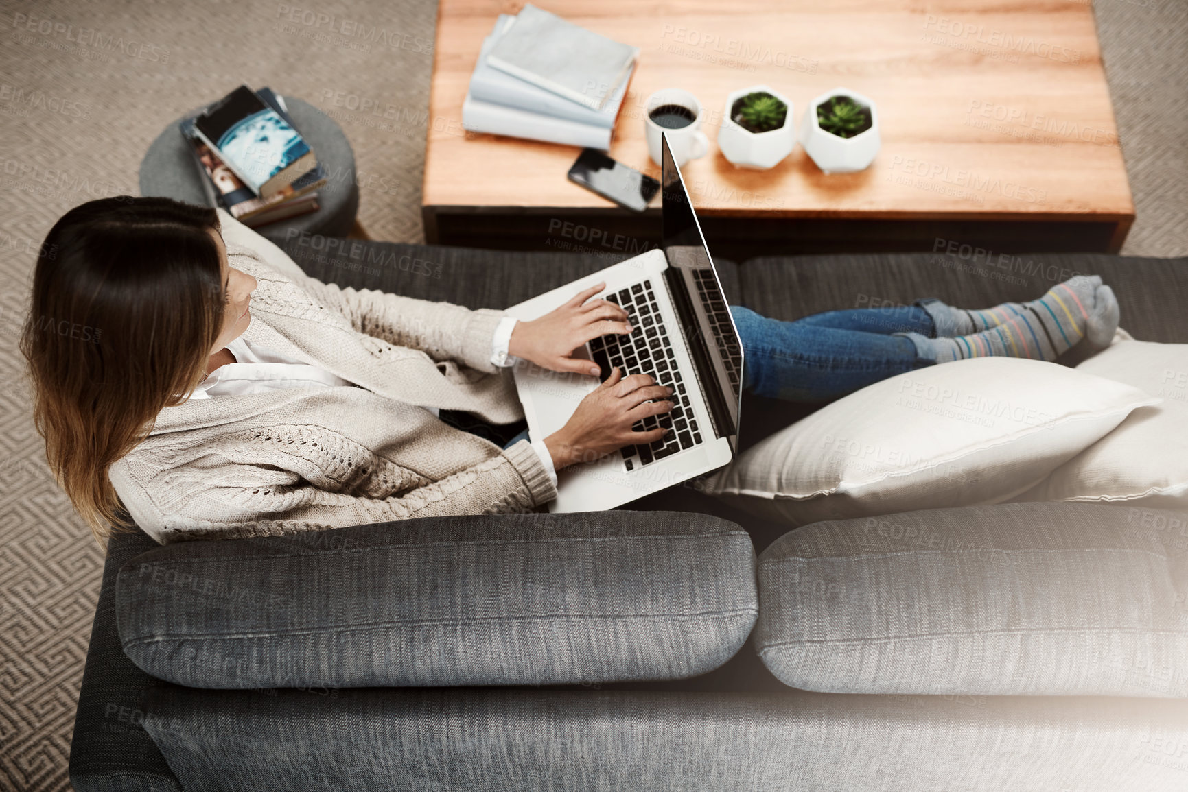 Buy stock photo Shot of an attractive young woman sitting on her sofa while working at home on her laptop