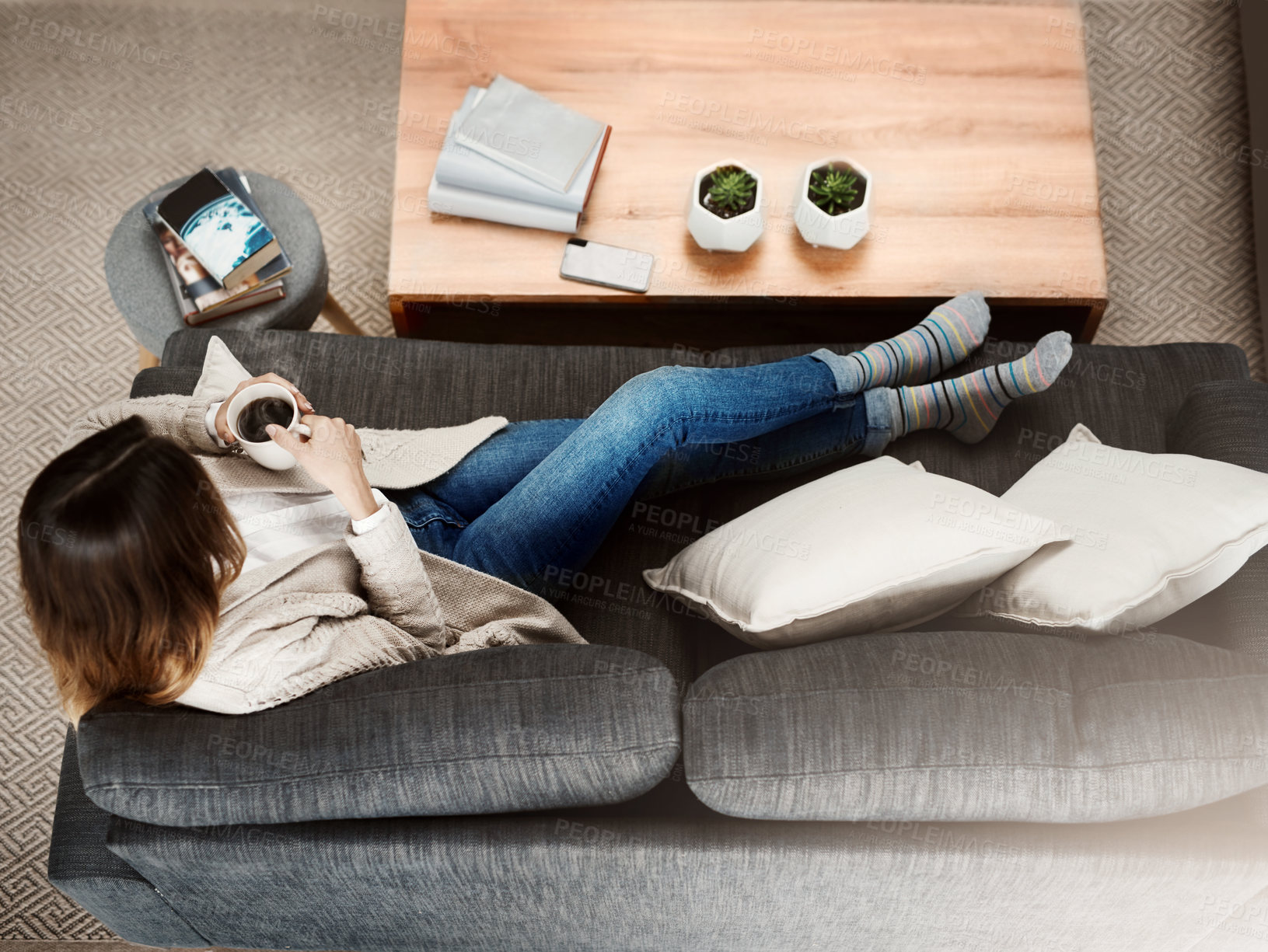 Buy stock photo Shot of an attractive young woman sitting on her sofa while  relaxing at home drinking coffee