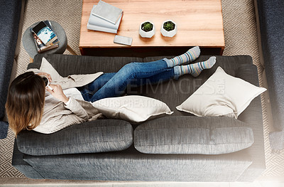 Buy stock photo Shot of an attractive young woman  sitting on sofa while relaxing at home drinking coffee