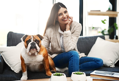 Buy stock photo Shot of an attractive young woman sitting on her sofa relaxing at home with her dog