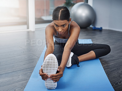 Buy stock photo Shot of an attractive young woman sitting down and doing stretching exercises on her gym mat at home