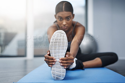 Buy stock photo Shot of an attractive young woman sitting down and doing stretching exercises on her gym mat at home