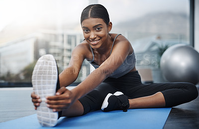 Buy stock photo Shot of a beautiful young woman smiling while sitting down and doing stretching exercises on her gym mat at home