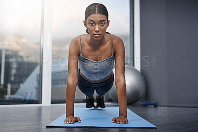 Buy stock photo Shot of an attractive young woman busy doing stretching exercises on her gym mat at home