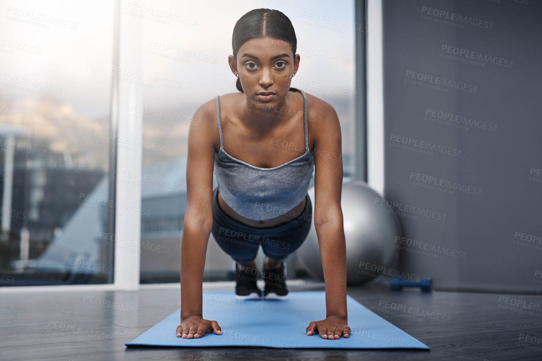 Buy stock photo Shot of an attractive young woman busy doing stretching exercises on her gym mat at home