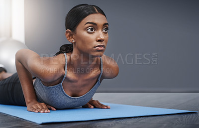 Buy stock photo Shot of an attractive young woman busy exercising on her gym mat at home