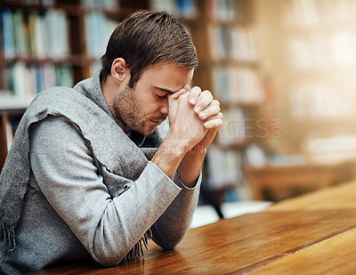 Buy stock photo Cropped shot of a handsome young man praying for help with his upcoming university exams