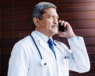 Buy stock photo Cropped shot of a handsome mature male doctor making a phonecall while working in his office