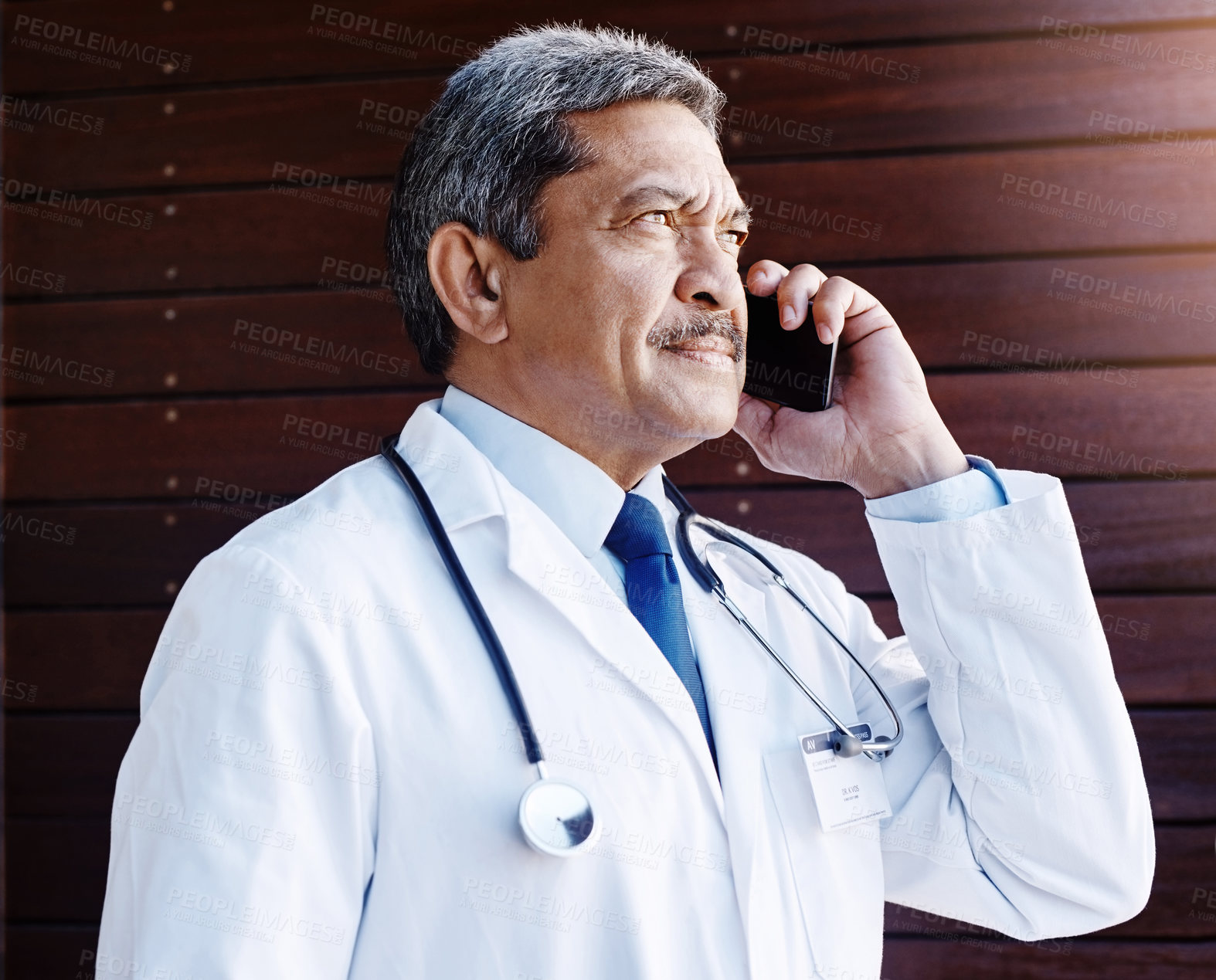 Buy stock photo Cropped shot of a handsome mature male doctor making a phonecall while working in his office