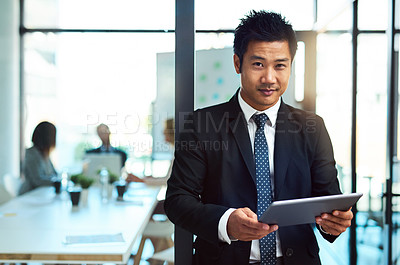 Buy stock photo Cropped shot of a handsome young businessman using a tablet in the workplace