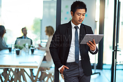 Buy stock photo Cropped shot of a handsome young man using a tablet in the workplace