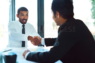 Buy stock photo Cropped shot of a two businessmen shaking hands in the workplace