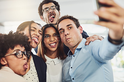 Buy stock photo Shot of a group of cheerful work colleagues taking a self portrait together inside of the office during the day