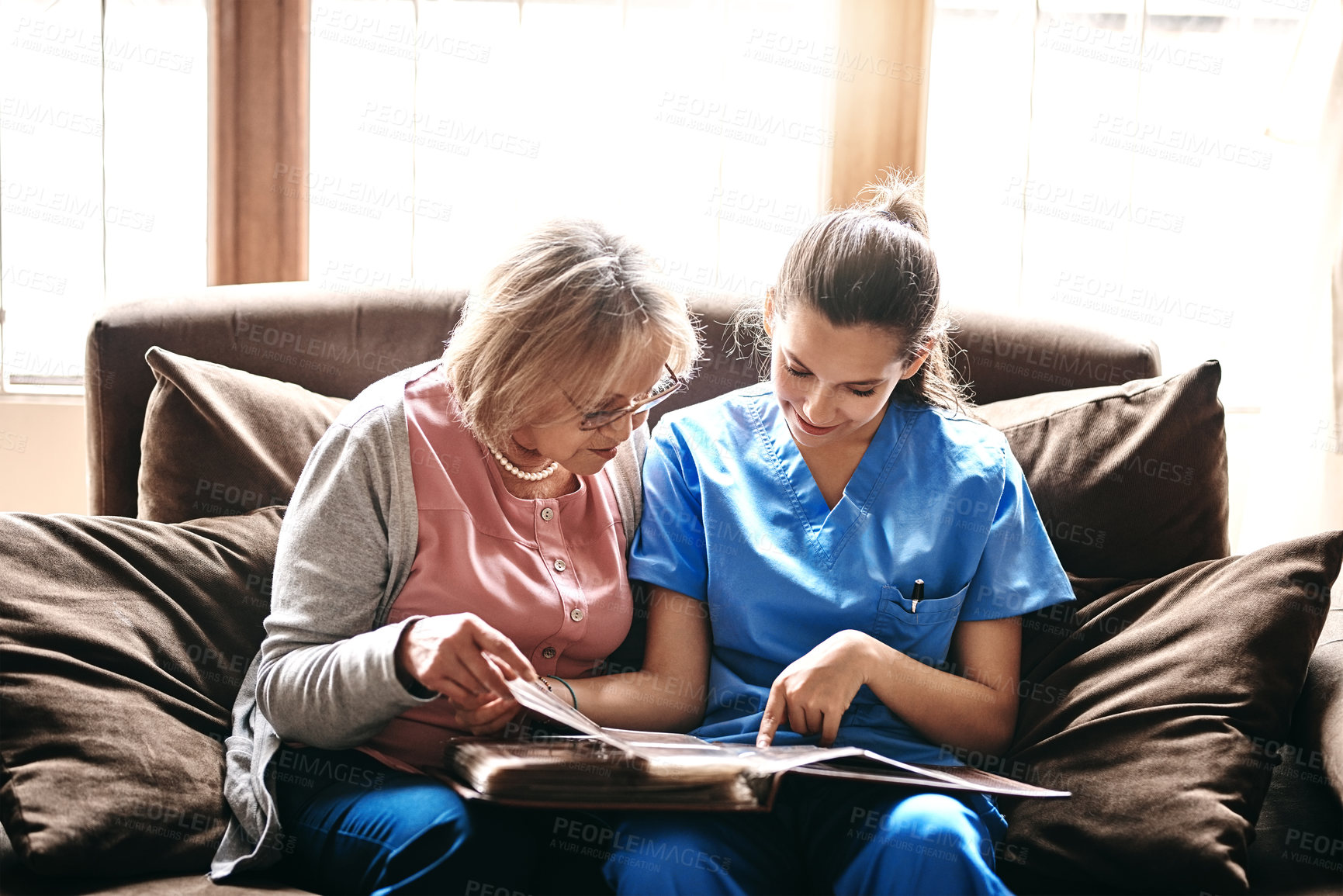 Buy stock photo Elderly, patient and nurse with photo album in home for memories, nostalgia or remember with support. Senior, woman or female caregiver in assisted living with talking of pictures, empathy or bonding