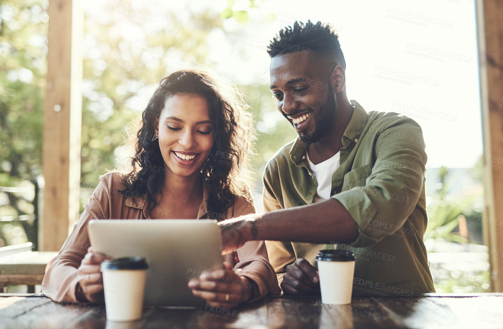 Buy stock photo Shot of a young couple using a digital tablet together at a cafe