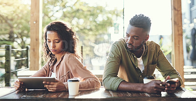 Buy stock photo Shot of two young people using their wireless devices in a coffee shop