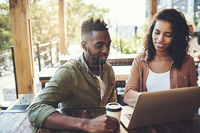 Buy stock photo Shot of a young couple using a laptop together in a coffee shop