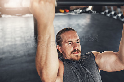 Buy stock photo Shot of a young man doing pull ups in a gym