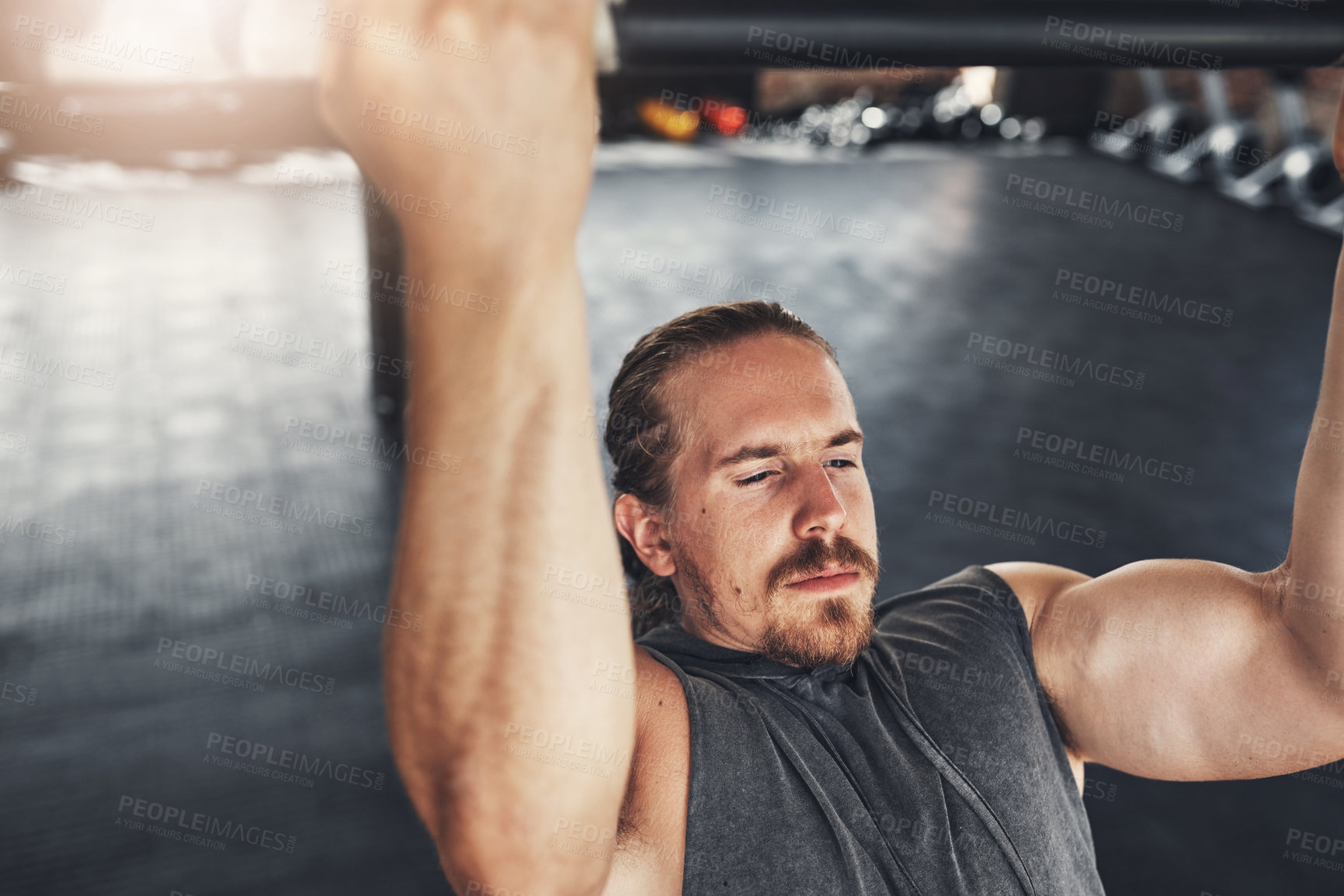 Buy stock photo Shot of a young man doing pull ups in a gym