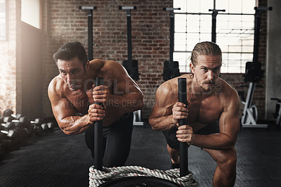 Buy stock photo Shot of two muscular young men pushing a weight sled in a gym