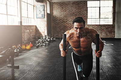 Buy stock photo Shot of a muscular young man pushing a weight sled in a gym