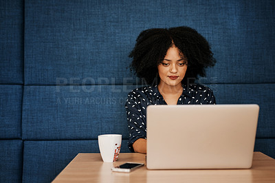 Buy stock photo Shot of a young focussed female designer working on her laptop at the office during the day