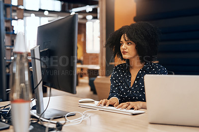 Buy stock photo Shot of a young focussed female designer working on her computer at the office during the day