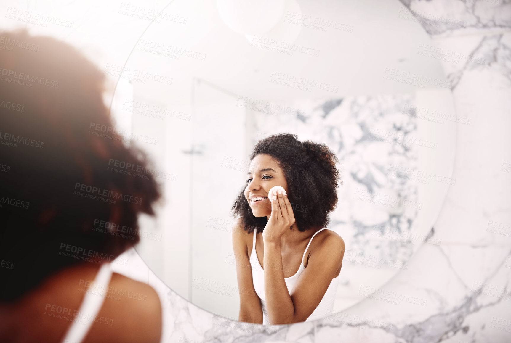 Buy stock photo Shot of an attractive young woman applying moisturizer to her face in the bathroom at home