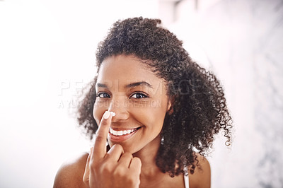 Buy stock photo Shot of an attractive young woman applying moisturizer to her nose in the bathroom at home
