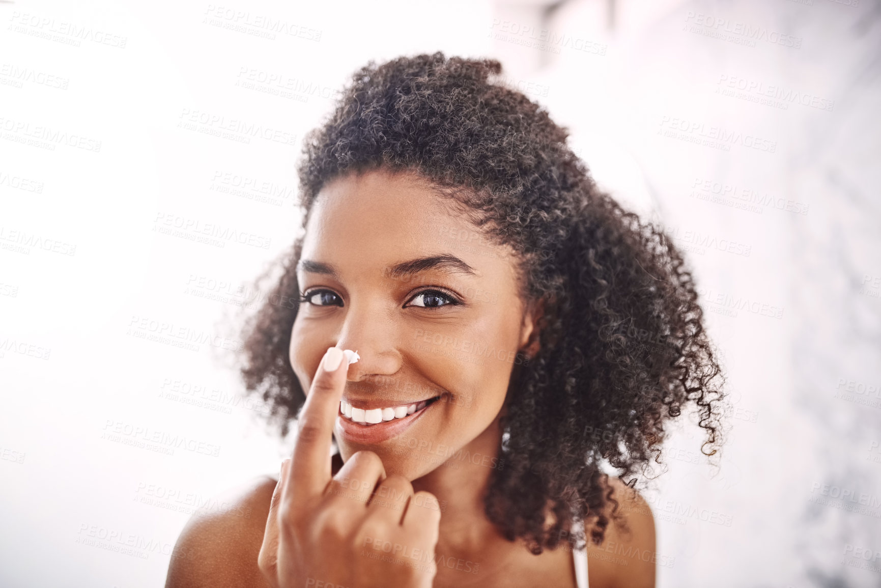 Buy stock photo Shot of an attractive young woman applying moisturizer to her nose in the bathroom at home