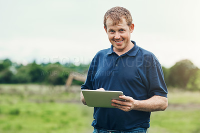 Buy stock photo Portrait of a cheerful young male farmer holding a digital tablet while standing outside on his land