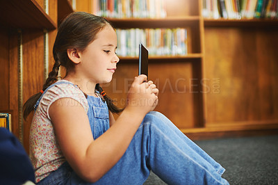 Buy stock photo Library, child and learning on tablet at school for knowledge, reading or online quiz in kindergarten. Bookshelf, student and girl studying on tech for english test, app and educational game on floor