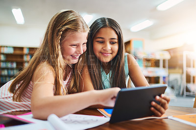 Buy stock photo Shot of two cheerful young school girls working together in a classroom with a digital tablet  at school during the day