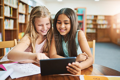 Buy stock photo Shot of two cheerful young school girls working together in a classroom with a digital tablet  at school during the day