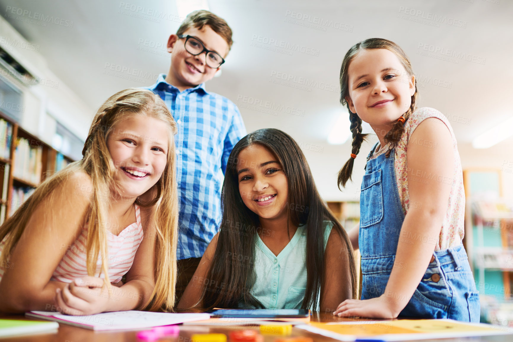 Buy stock photo Portrait of a group of cheerful young school children working together inside of a classroom during the day