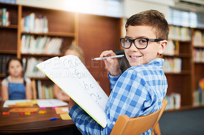 Buy stock photo Happy boy, portrait or student with book at library for learning, studying or smart education in school. Young, child or kid with smile, glasses or notebook for alphabet, literature or writing skills