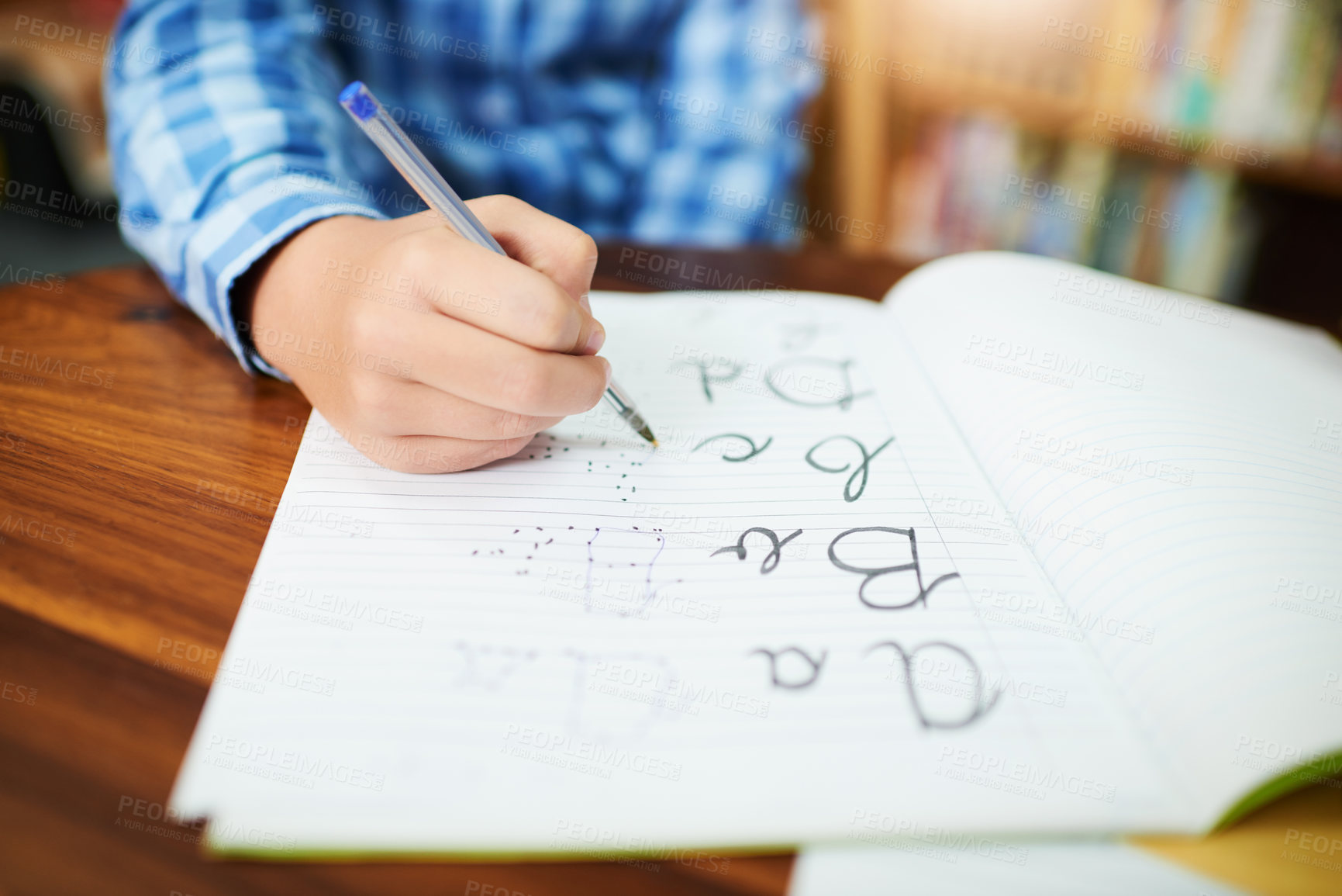 Buy stock photo Closeup of an unrecognizable young boy working and writing inside of a book at school during the day