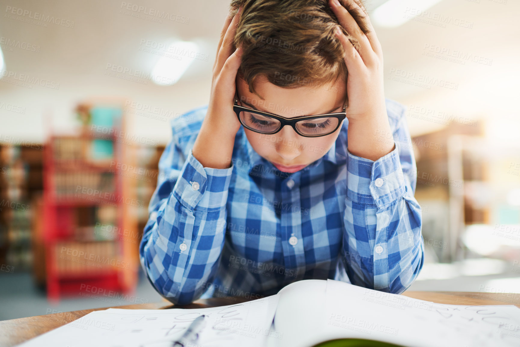 Buy stock photo Shot of a young boy looking stressed out while working in class at school