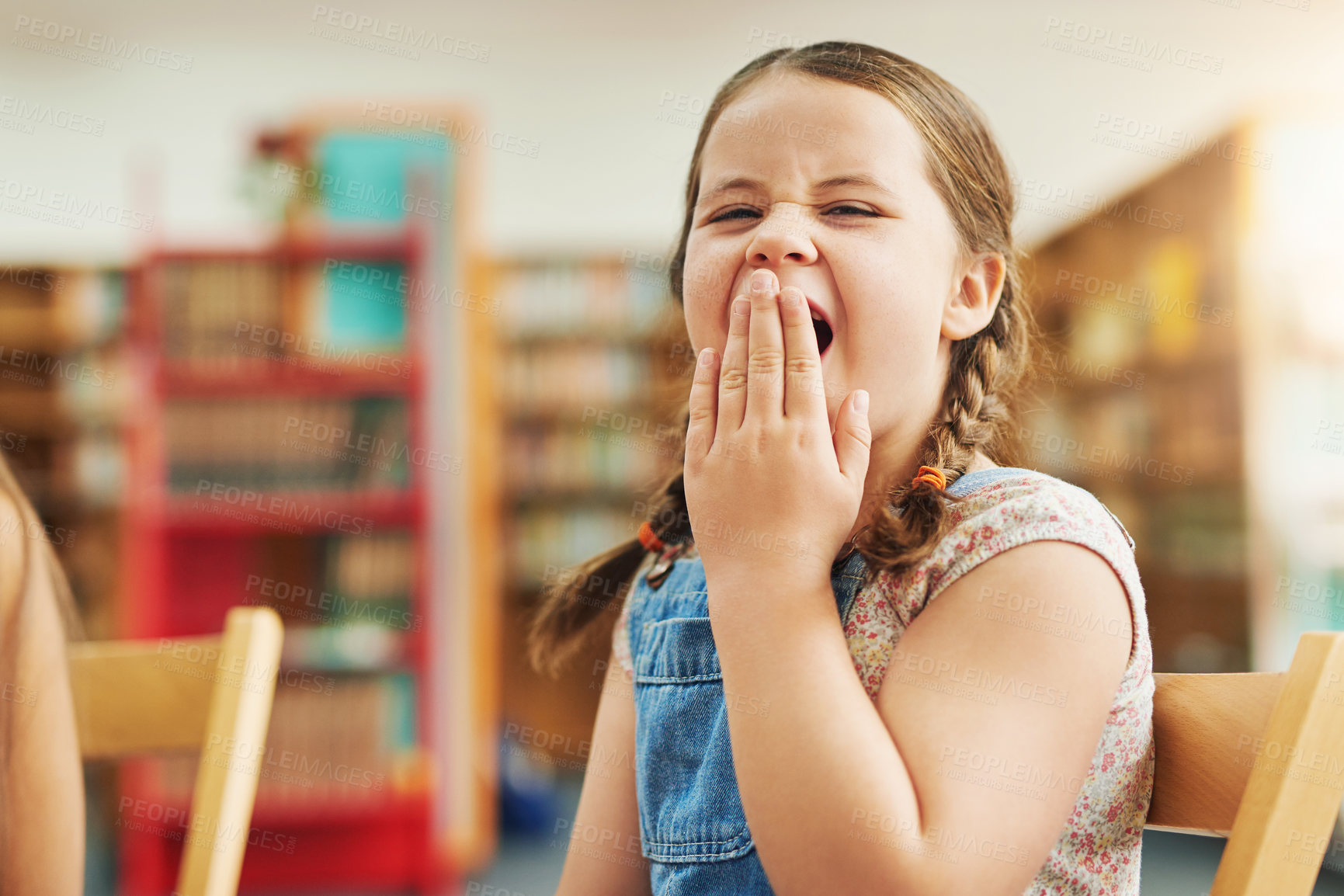 Buy stock photo Girl, child and yawning in classroom for portrait, tired and lazy for education, development and progress. Kid, fatigue and brain fog with scholarship, study or exhausted at school library in Germany