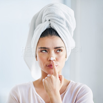 Buy stock photo Shot of a beautiful young woman applying moisturizer to her skin in the bathroom at home